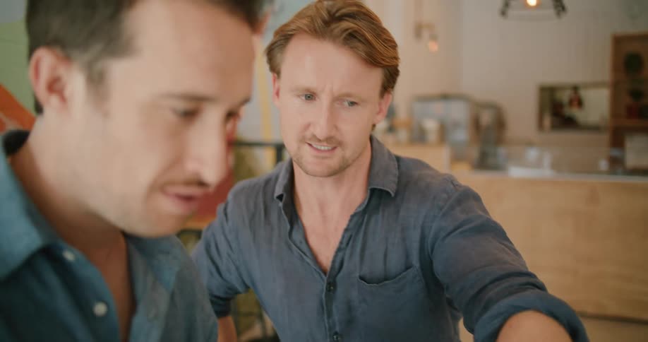 Two men are talking in a store and looking at a laptop