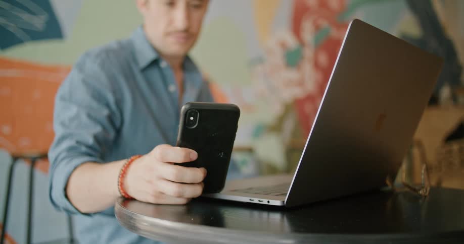 A man picks up his cell phone from the table