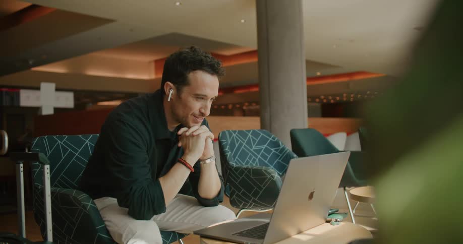 A man leans forward talking to his laptop