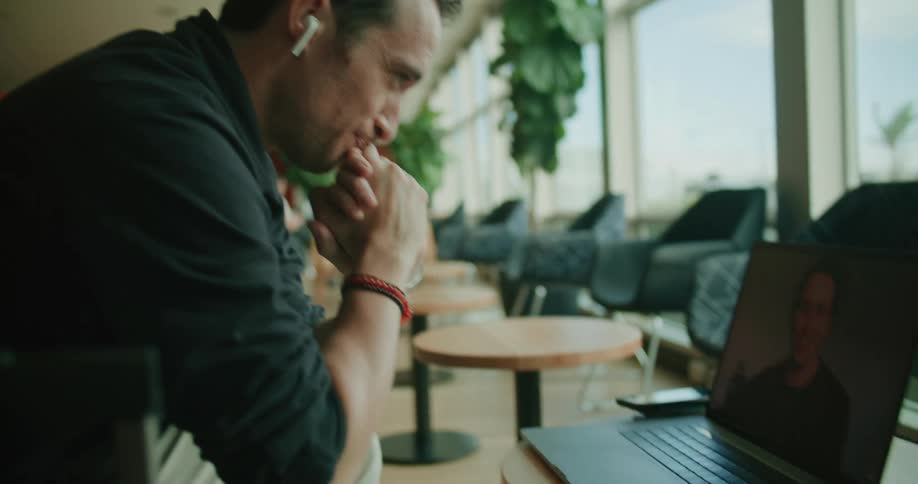 A man video chatting on a laptop while sitting in a chair