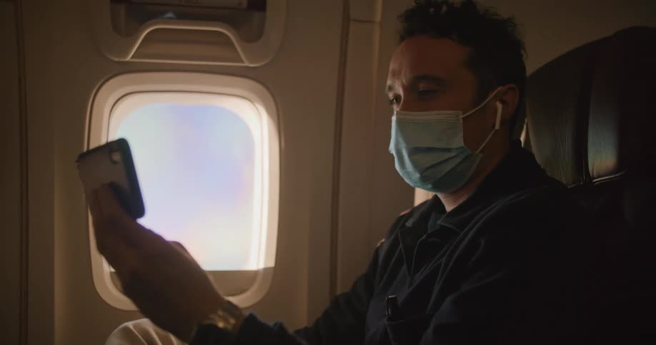 A man in an airplane with a cell phone