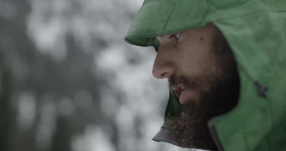 A man wearing a green hood moves down