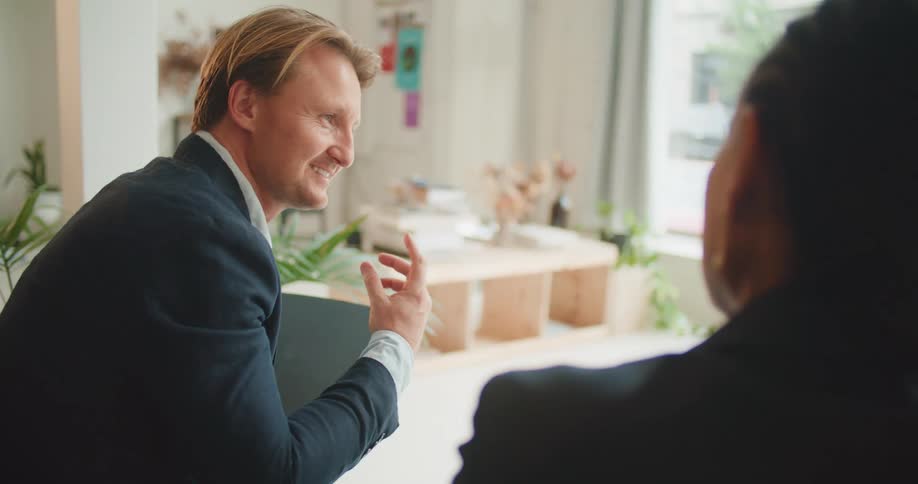 A man and woman sit in an office together and talk