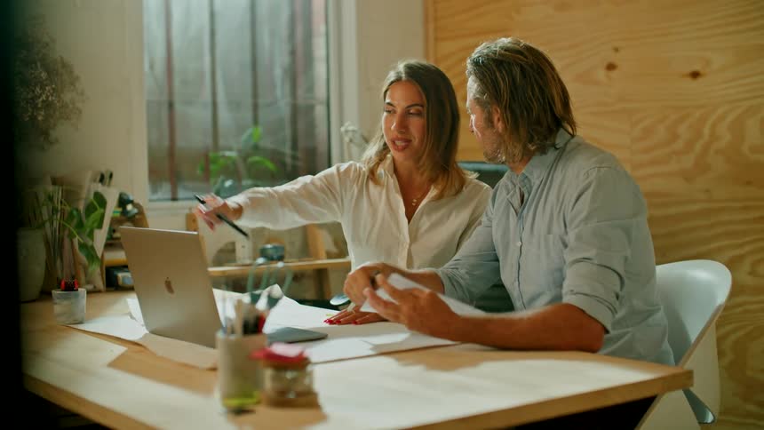 A man and woman are talking together and sitting at a table
