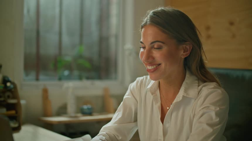 An office lady smiles and waves to her laptop while she is working