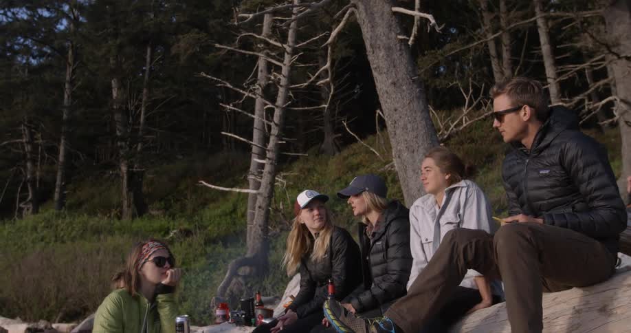 A group of people are sitting on a rock talking