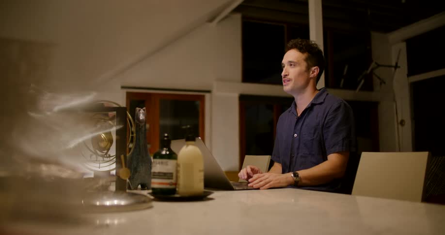 A man is sitting at a table with a laptop at night