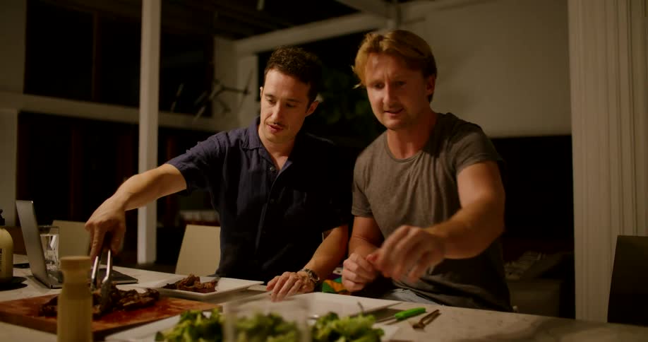 Two men at home put food on their plates
