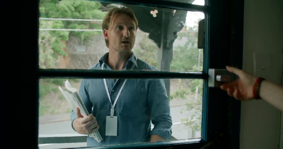 A salesman knocks on the front door of a home as traffic passes by behind him