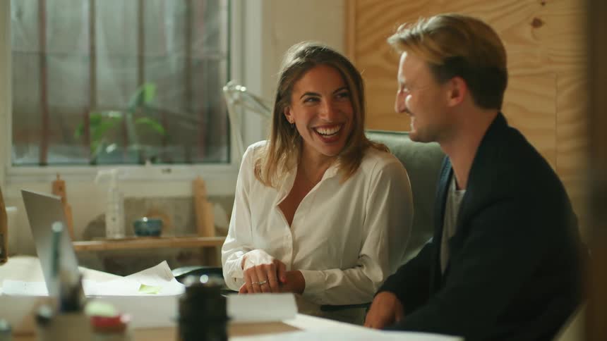 Two people talk and laugh in the office