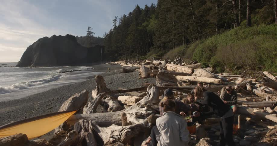 Group of people sitting around a campsite on the beach in the daytime