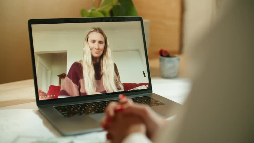 A woman talking to someone on a laptop