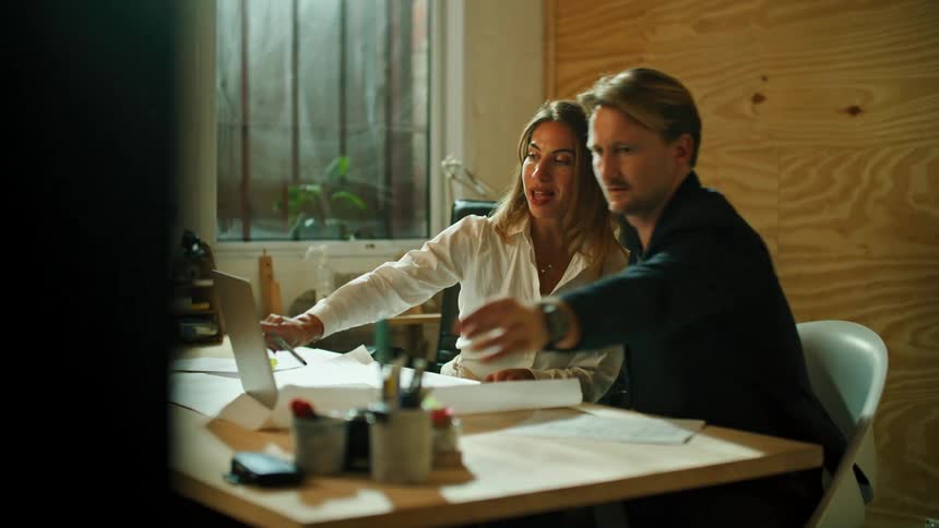 A woman and man look at a laptop in the office