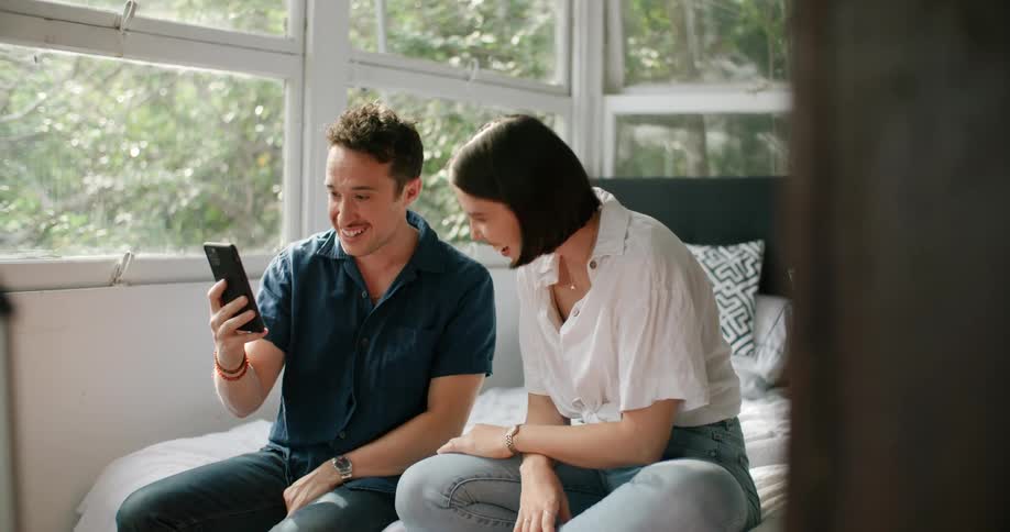 A man and woman laughing at a phone