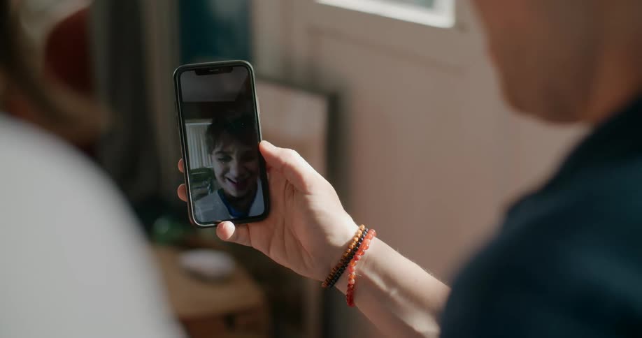 Youth on video call on mobile phone laughs with those making call