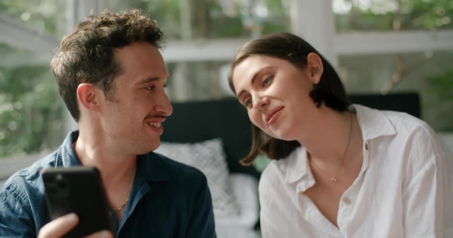 A man and woman smiling while video chatting on a smartphone
