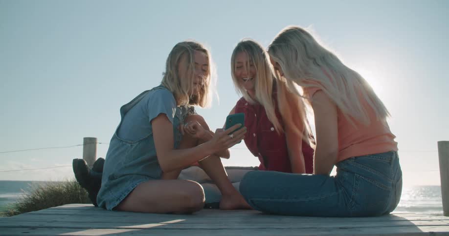 Three women that are friends are sitting at the beach