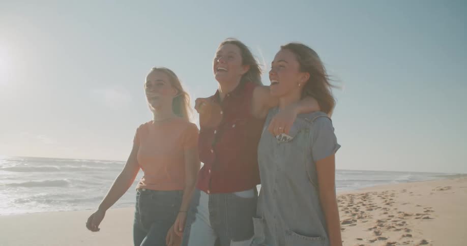 A woman walks down the beach with her two teenage daughters