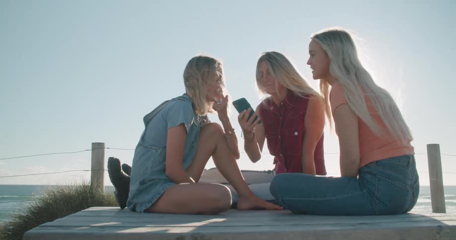 Three women sitting around a cell phone