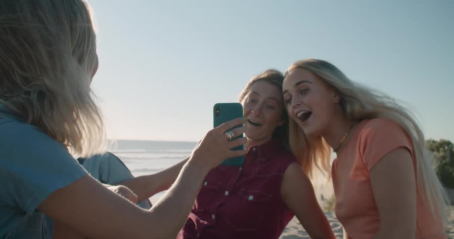 Three women that are friends are sittingat the beach during the day