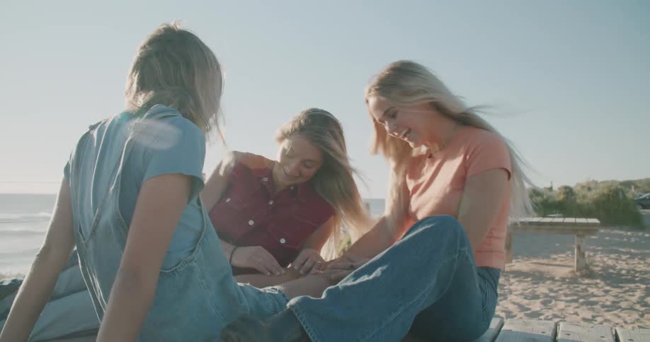 A group of women sitting at the beach laughing