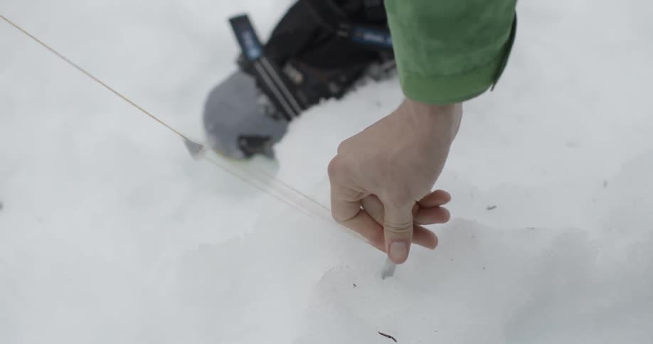 A person places a marker in the snow