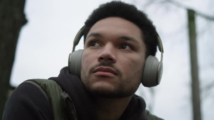 A man listening to headphones outside on a chilly day