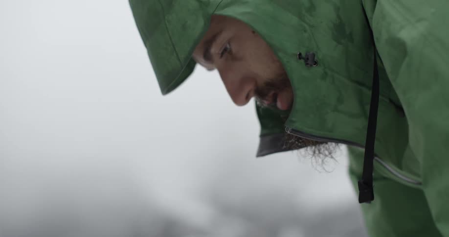 A man in a green coat looks down