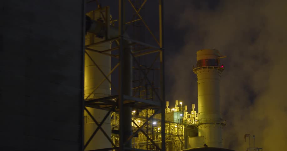 White clouds of steam and vapor rising from a power plant at night