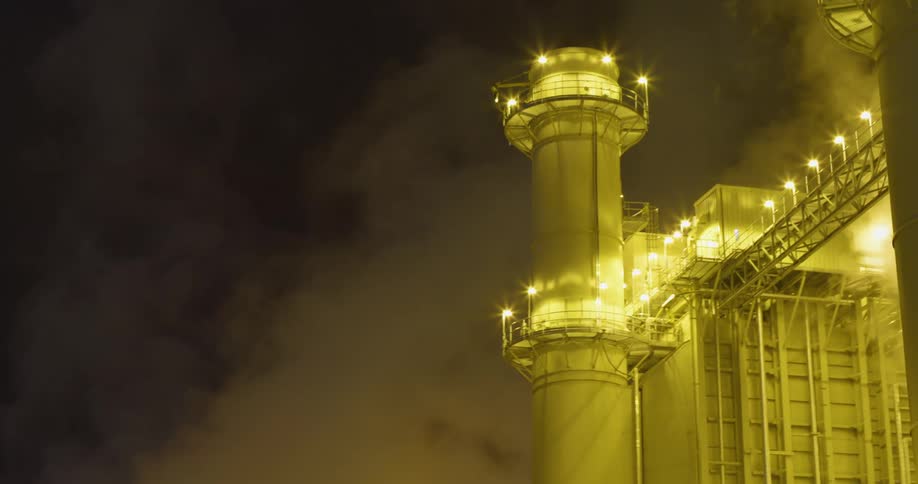 Clouds of steam and vapor rising from a power plant at night