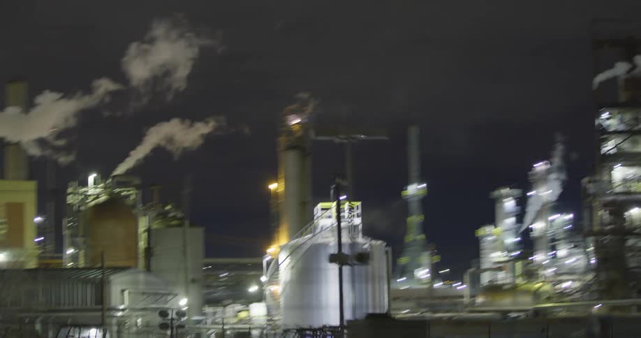 Exterior of an industrial park with smoke and lights at night