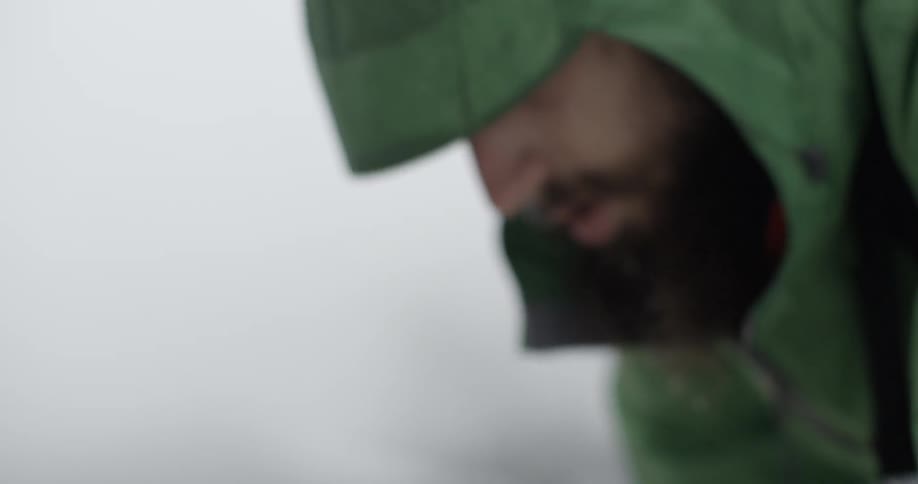 A man is crouching as he ties a tent down
