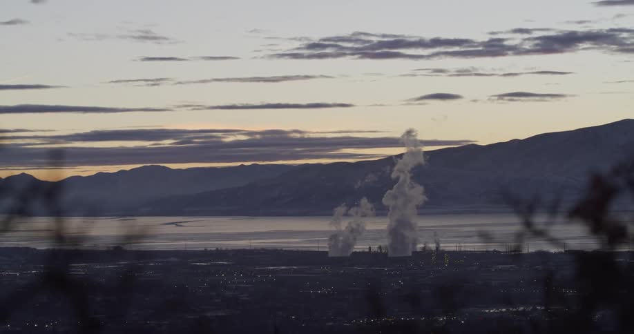 Landscape with mountains a body of water and smoke at dusk