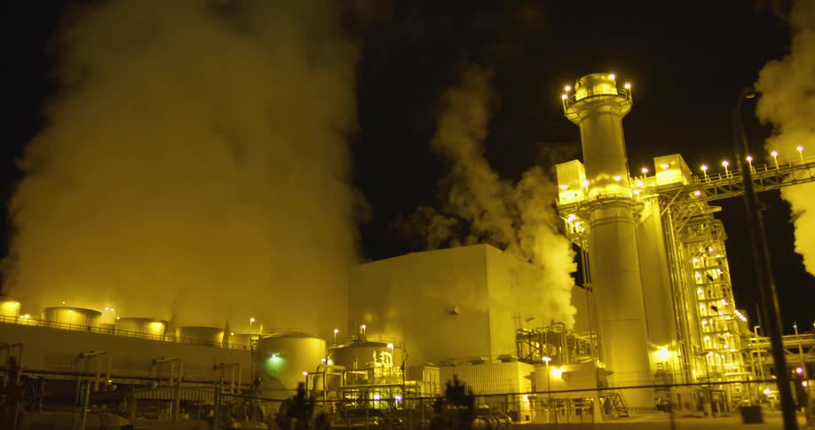 Clouds of steam and vapor rising from a power plant at night