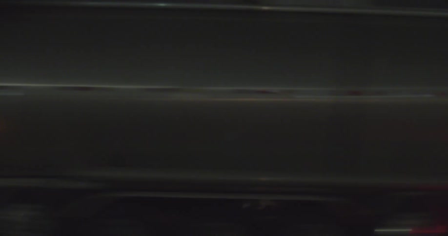A truck driving on the highway passes in front of a factory at night