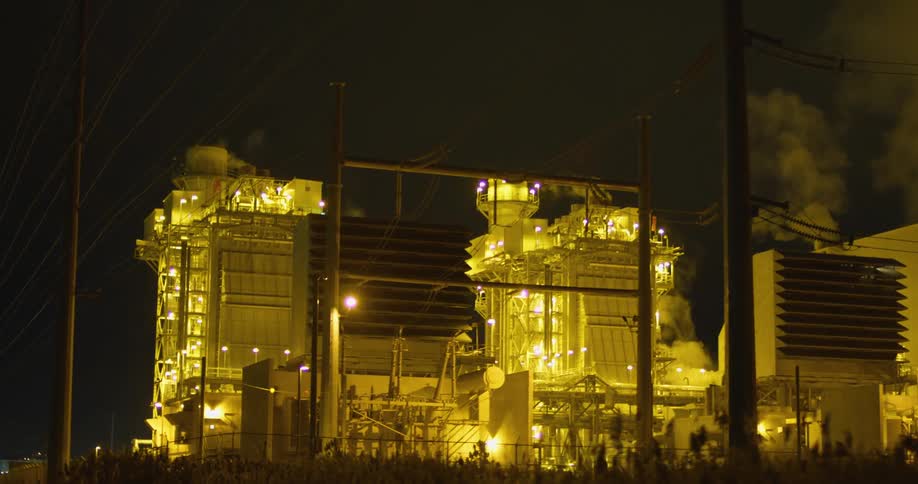 Clouds of steam and vapor rising from a power plant at night