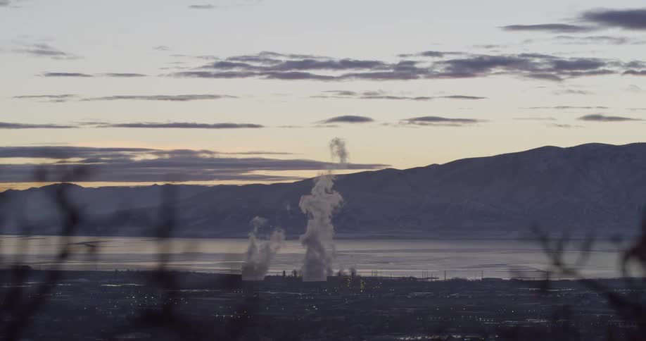Smoke rises from a power plant located in the middle of a city next to the water