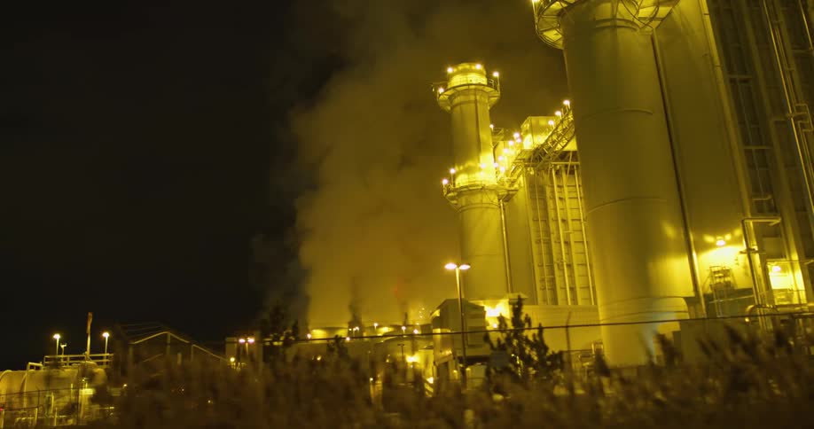 Clouds of steam and vapor rising from a power plant at night