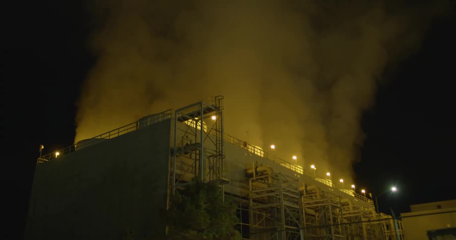 Clouds of steam and vapor rising from a power plant at night