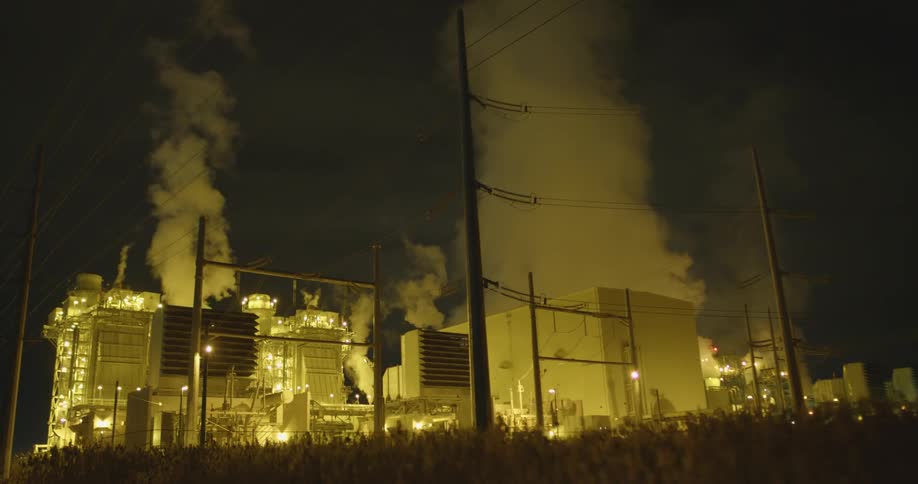 Exterior of an industrial area at night with lights and steam in the air