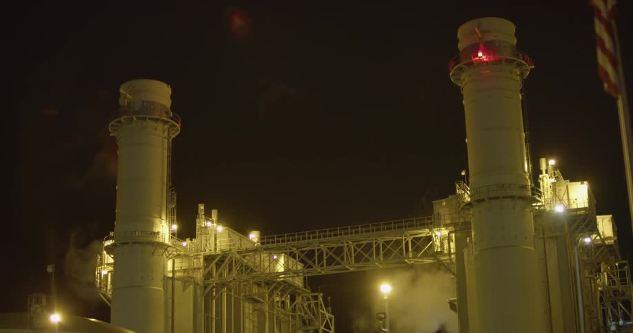 White clouds of steam and vapor rising from a power plant at night