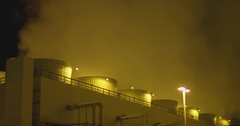 Clouds of steam and vapor rising from a power plant at night