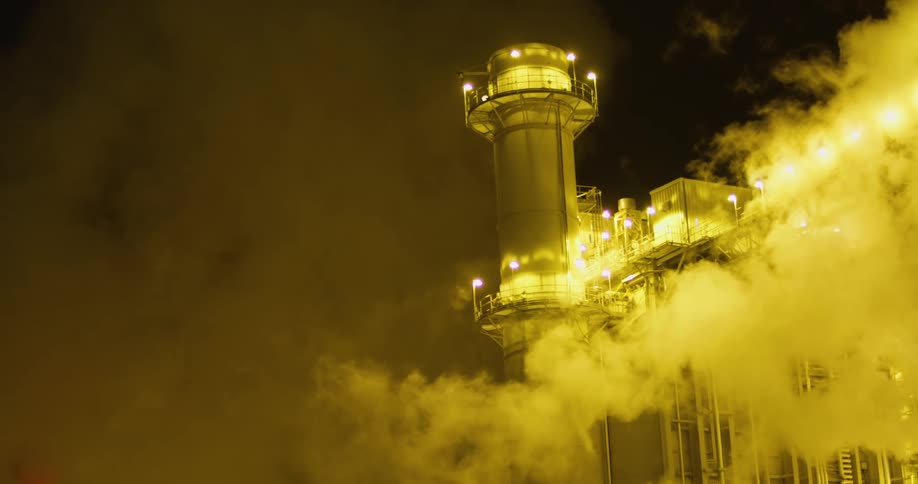 Clouds of steam and vapor rising from a power plant at night