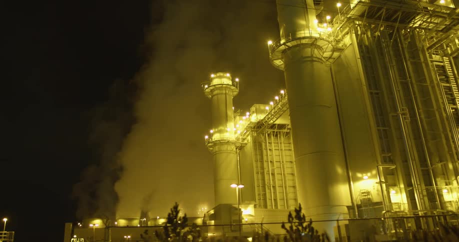 White clouds of steam and vapor rising from a power plant at night