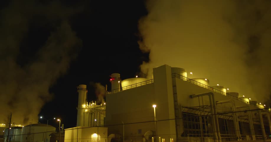 Clouds of steam and vapor rising from a power plant at night
