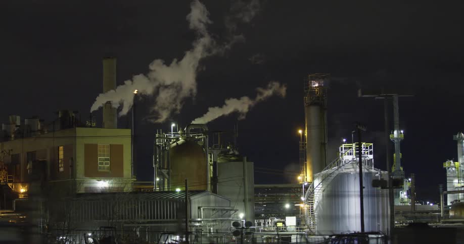 A large industrial park with equipment containers buildings and smoke at night