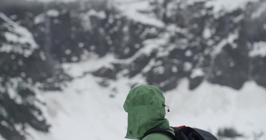 A man slowly turns around to face a mountain behind him
