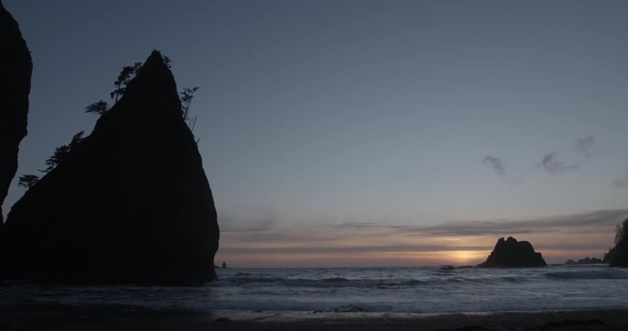 Waves are hitting a beach at sunset