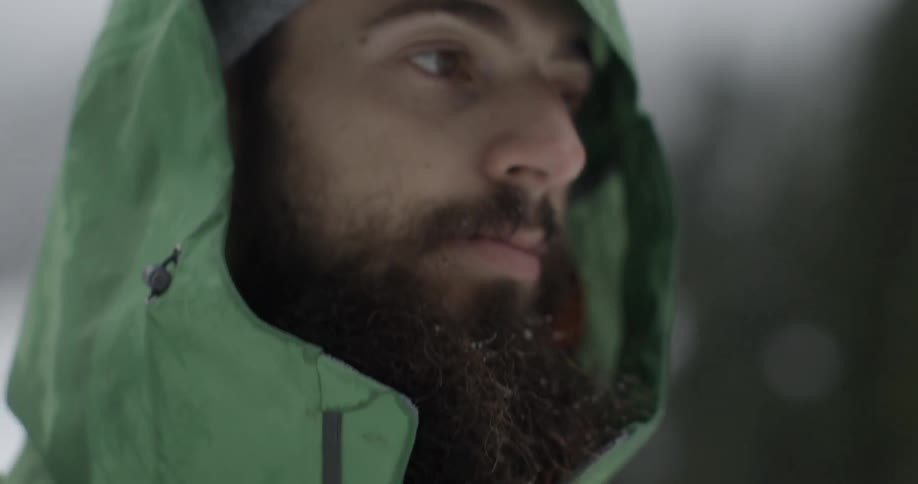 A man wears a hooded jacket outside on a cold day