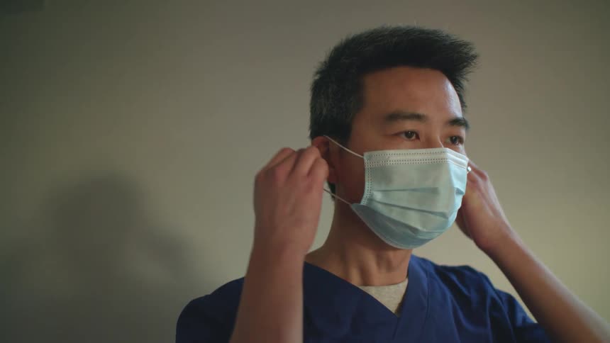 A young man takes a mask off of his face